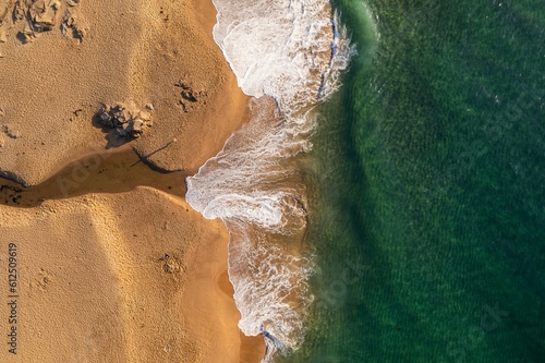 Drone top shot over sea water and sandy beach