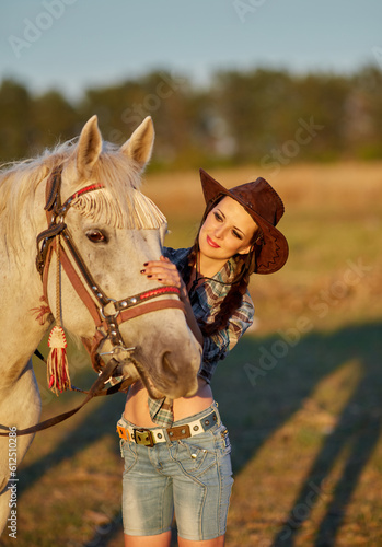 Happy young woman cowgirl in hat standing and hugging her horse © Ryzhkov Oleksandr