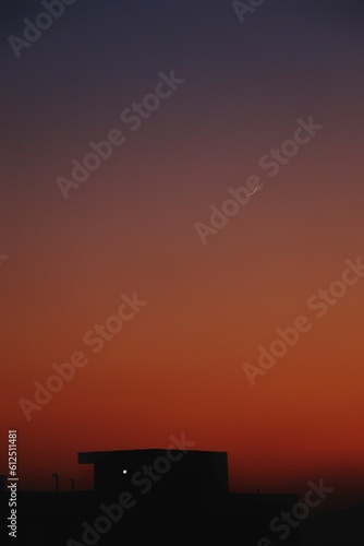 Silhouette houses in a distance under orange evening sky, vertical shot