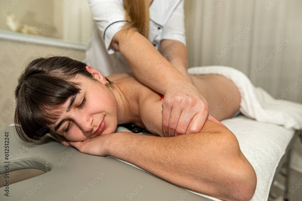 Beautiful caucasian woman client receiving relax massage on back in spa salon Beautiful caucasian woman client receiving relax massage on back in spa salon