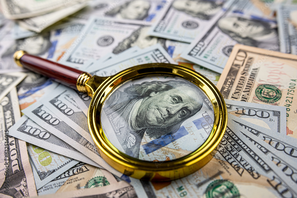 Golen magnifying glass on different dollars money as financial background Golen magnifying glass on different dollars money as financial background