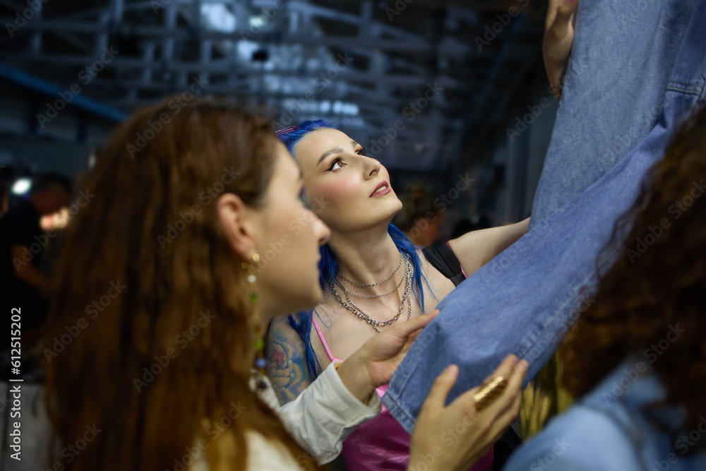 Lesbian couple shopping for jeans clothes at a flea market. Two young diverse women choosing vintage denim clothes in a thrift shop. Lesbian couple shopping for jeans clothes at a flea market. Two young diverse women choosing vintage denim clothes in a thrift shop.