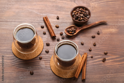 Drink coasters with glasses of coffee, cinnamon and beans on wooden table