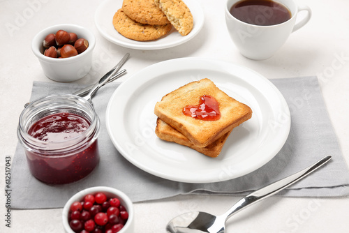Plate of tasty toasts with cranberry jam on light background