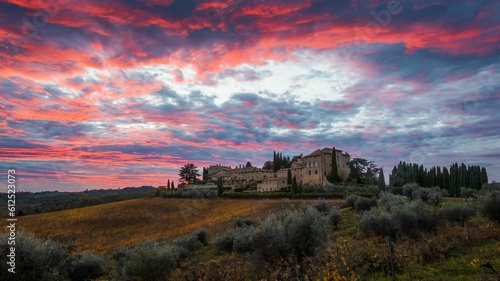 Beautiful view of green fields with houses in Castello di Lucignano, Siena, Tuscany, Italy at sunset