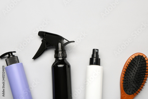 Hair sprays with brush on grey background, closeup