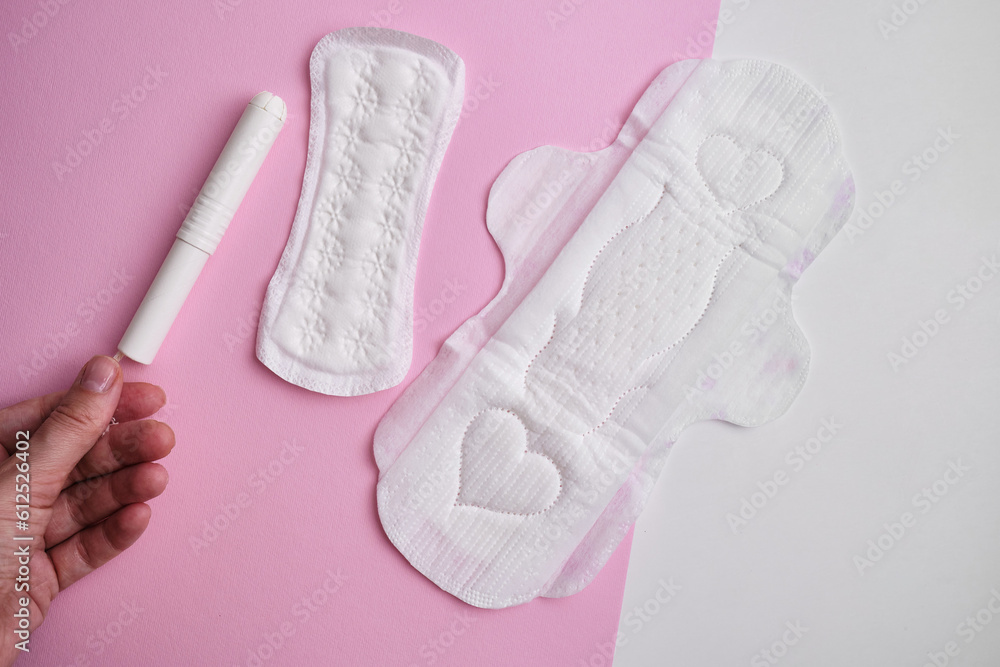 Women's pads and tampon. Sanitary pads lie next to a tampon on an isolated background on a pink and white background. The concept of health, feminine hygiene and the menstrual cycle Women's pads and tampon. Sanitary pads lie next to a tampon on an isolated background on a pink and white background. The concept of health, feminine hygiene and the menstrual cycle