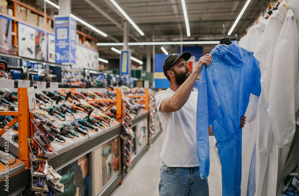 Fototapeta premium A man chooses a protective suit in a hardware store.