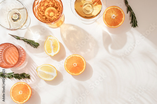 Summer orange cocktails with citrus fruits on white background. Hard seltzer, lemonade, refreshing drinks, low alcohol mocktails, summer party concept. Trendy palm leaf shadow and sunlight, sun.