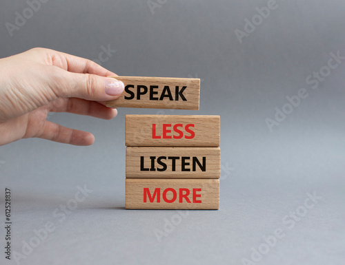 Speak less Listen more symbol. Wooden blocks with words Speak less Listen more. Beautiful grey background. Businessman hand. Business and Speak less Listen more concept. Copy space.