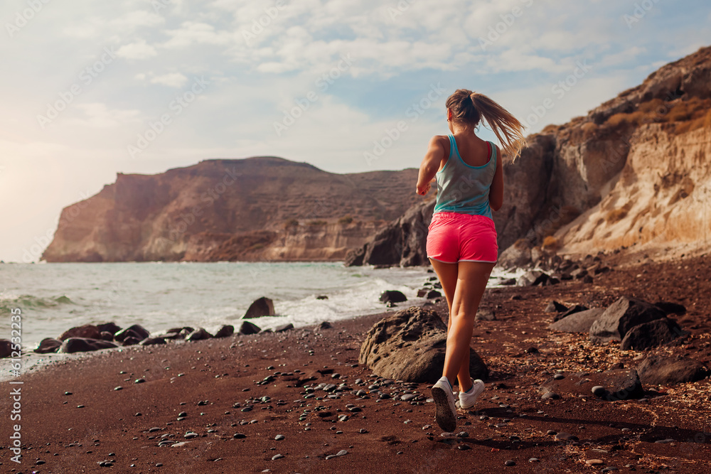 Woman running on Red beach on Santorini island. Female runner jogging during outdoor workout enjoying view