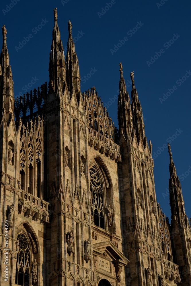 Vertical shot of the Duomo di Milano cathedral against a blue sky in Milan, Italy