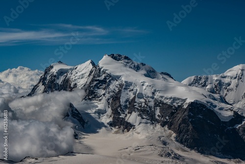 Beautiful shot of snowy mountains against a blue sky on a sunny day © Ploxien/Wirestock Creators