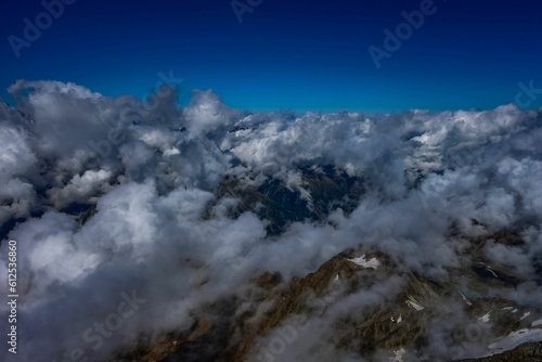 Beautiful shot of clouds covering mountains on a sunny day © Ploxien/Wirestock Creators