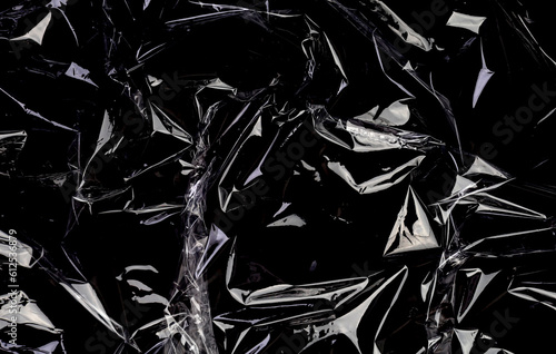 Wrinkled plastic wrap texture on a black background. Transparent cellophane package wallpaper
