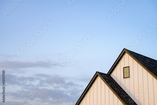 two peaks of white house with dark roof under blue sunset sky