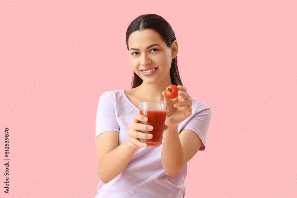 Young woman with glass of vegetable juice and tomato on pink background Young woman with glass of vegetable juice and tomato on pink background