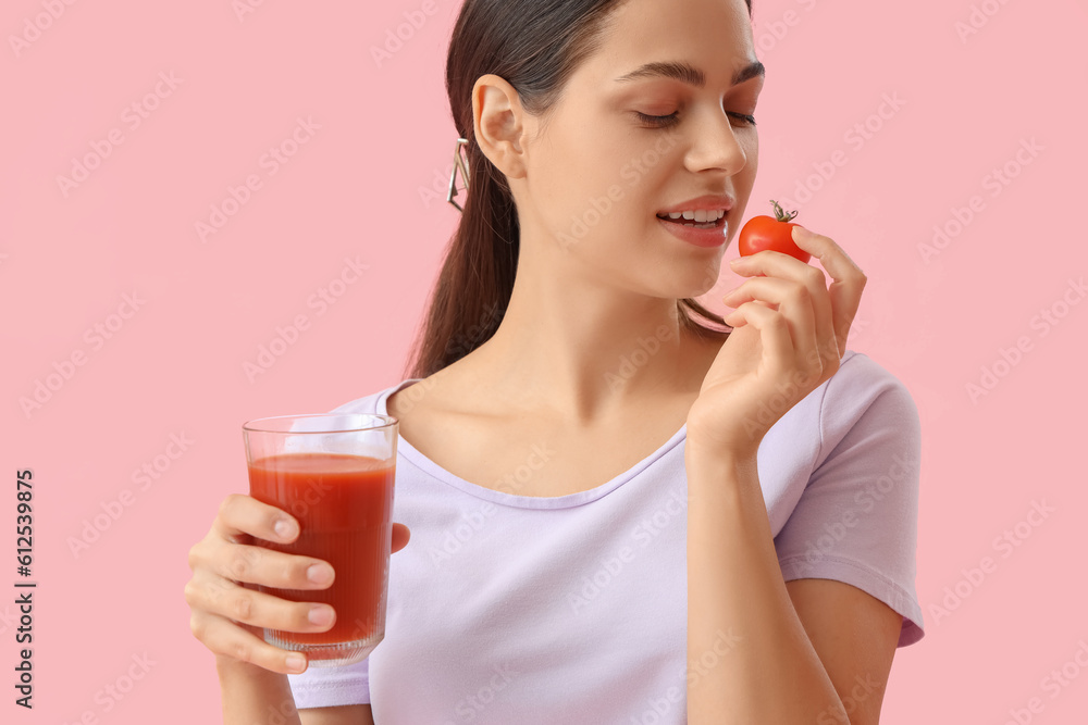 Young woman with glass of vegetable juice eating tomato on pink background Young woman with glass of vegetable juice eating tomato on pink background