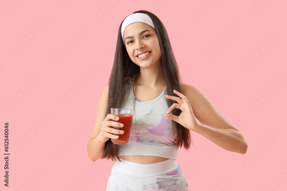 Sporty young woman with glass of vegetable juice showing OK on pink background Sporty young woman with glass of vegetable juice showing OK on pink background