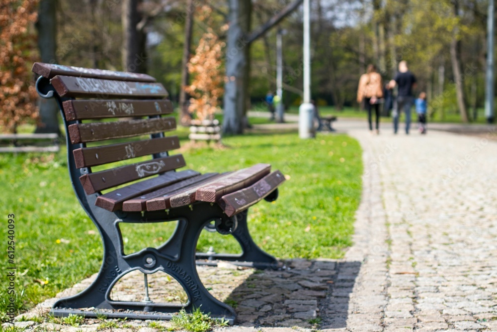 Bench at the Stromovka Royal Park with a family walking on the blurred background in Prague