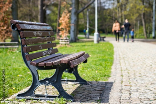 Bench at the Stromovka Royal Park with a family walking on the blurred background in Prague © Martin Haushalter/Wirestock Creators