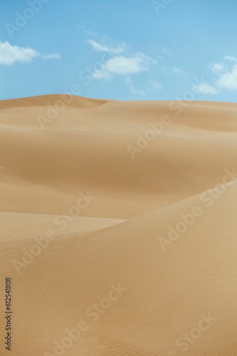 Vertical shot of a an empty desert dunes under a blue sky