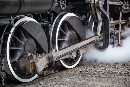 Closeup of black steam locomotive wheels on a rails