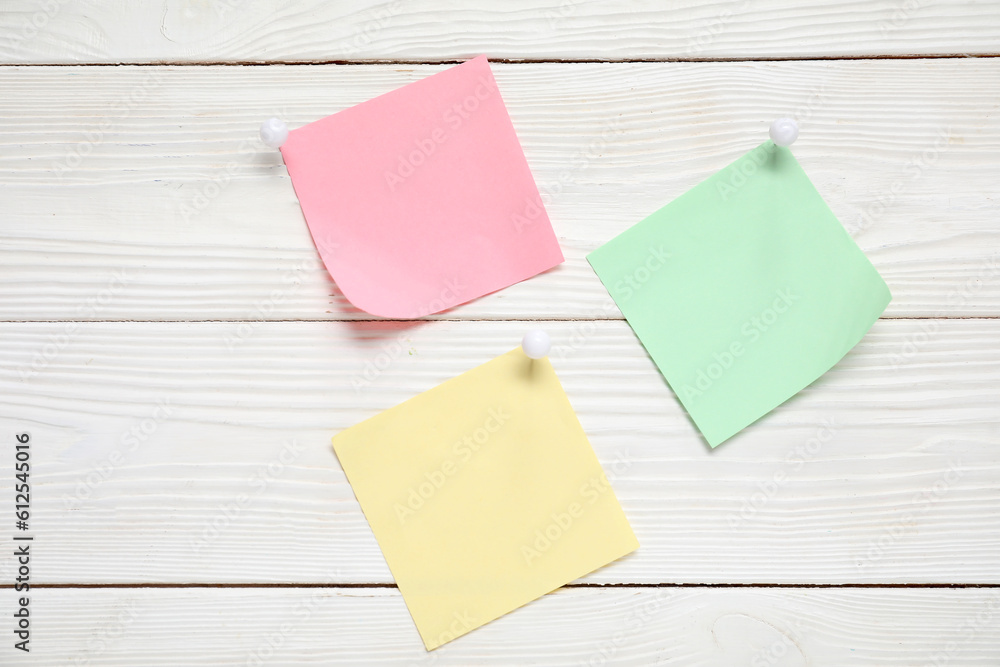 Sticky notes with pins on white wooden background Sticky notes with pins on white wooden background
