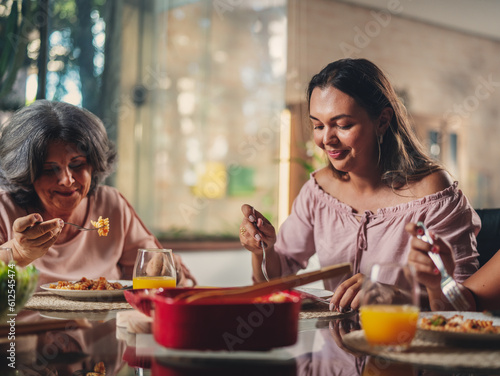 Elderly mother and her daughter sitting at the table eating during mother's day lunch
