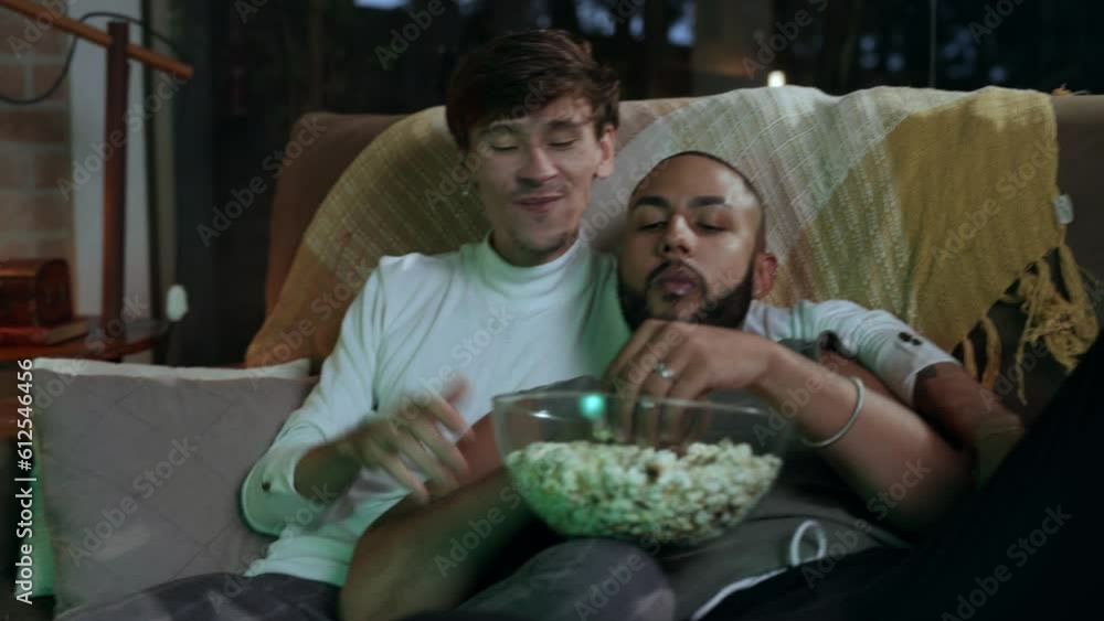 homem caucasiano abraçado com seu namorado negro sofá da sala comendo pipoca no dia dos namorados no brasil homem caucasiano abraçado com seu namorado negro sofá da sala comendo pipoca no dia dos namorados no brasil