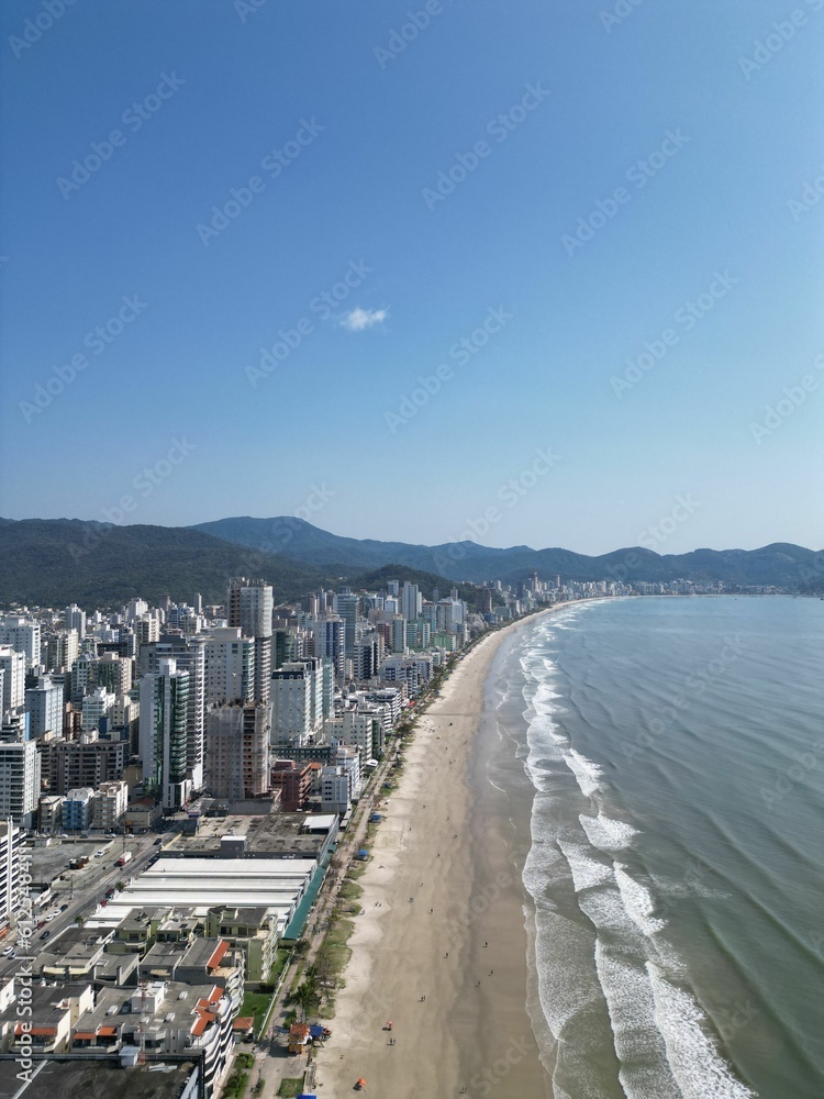 Aerial vertical shot of buildings facing the coastline under a clear blue sky