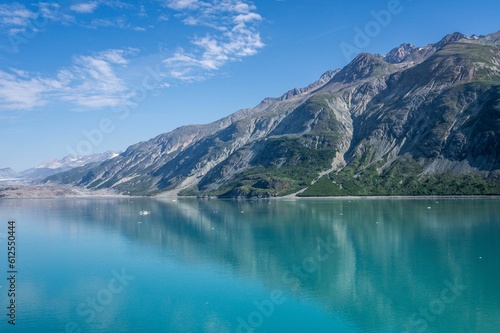 Calm blue sea with big mountains in the background on a sunny day under the blue sky © Colton Menke/Wirestock Creators