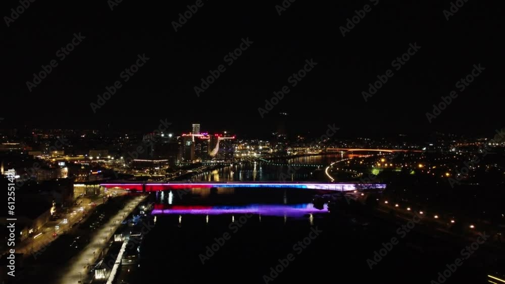 Illuminated bridge over the river in a city at night