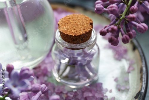Bottles of cosmetic oil with beautiful lilac flowers and sea salt  closeup