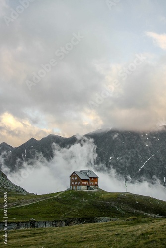 Vertical shot of a beautiful house with mountains and a cloudy sky in the background