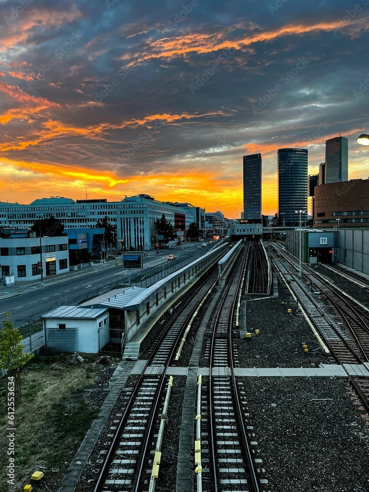 Fototapeta premium Vertical shot of a sunset over the railroad and buildings.