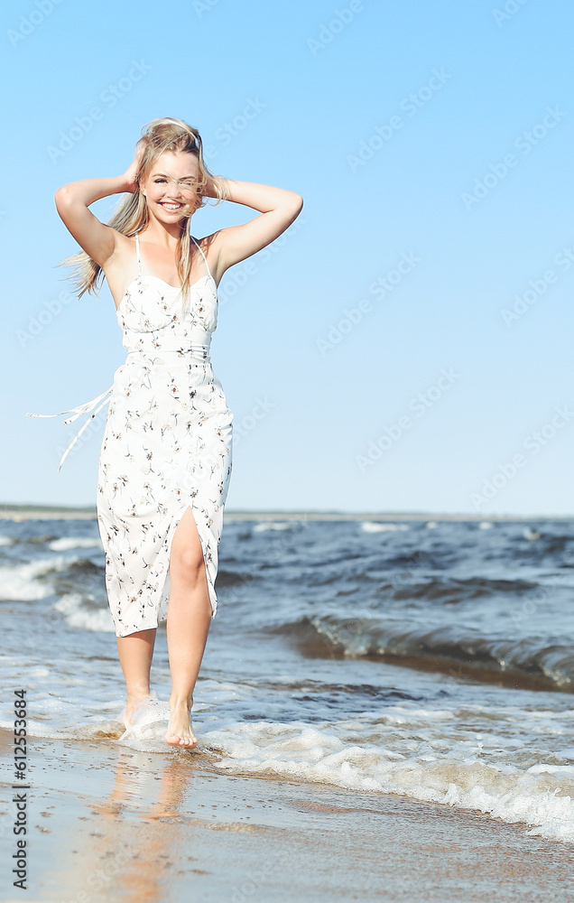 Happy blonde beautiful woman having fun on ocean beach while dancing in waves.