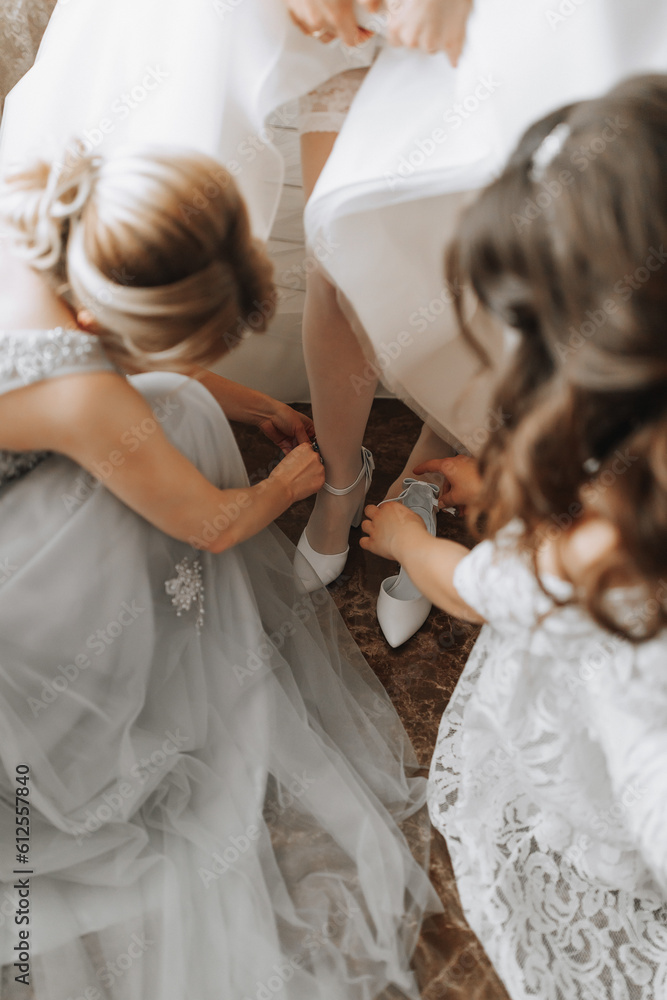 Girlfriends help the bride put on her wedding shoes. Beautiful female legs close-up Girlfriends help the bride put on her wedding shoes. Beautiful female legs close-up