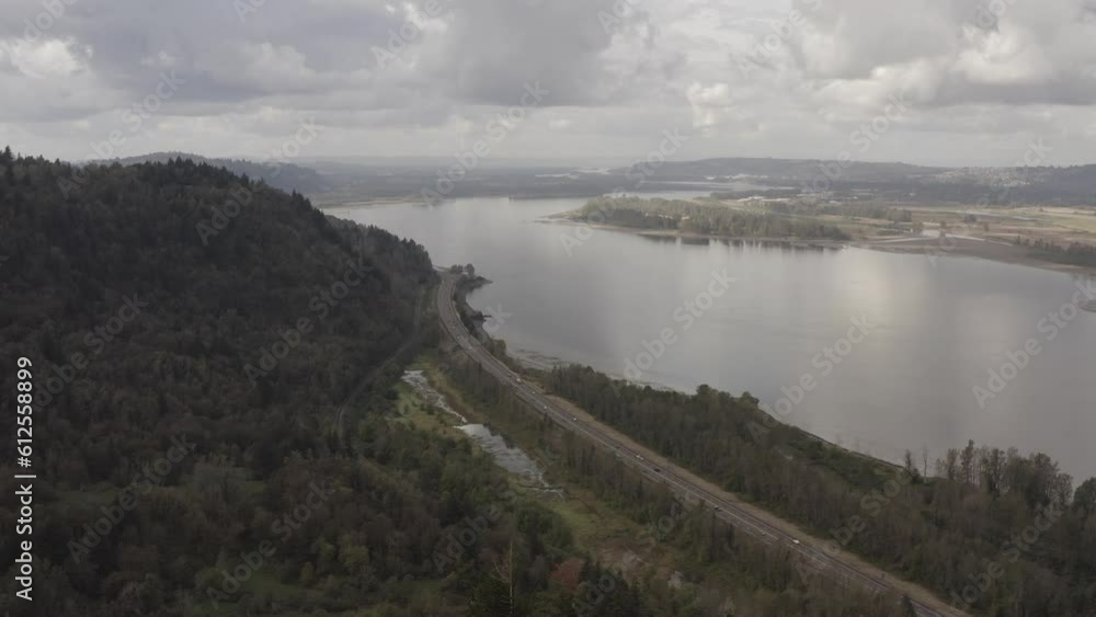 Aerial view of lakeshore with greenery and hills under cloudy sky on a gloomy day Aerial view of lakeshore with greenery and hills under cloudy sky on a gloomy day