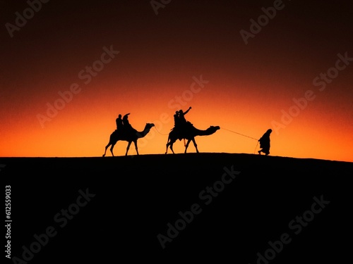 Silhouettes of caravan in a desert at sunset