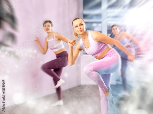 Positive women engaged in active dancing in the studio during a group workout