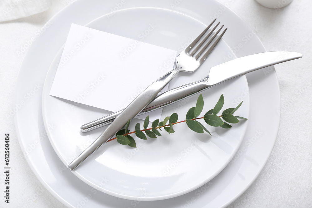 Stylish table setting with blank card and plant branch on white background Stylish table setting with blank card and plant branch on white background