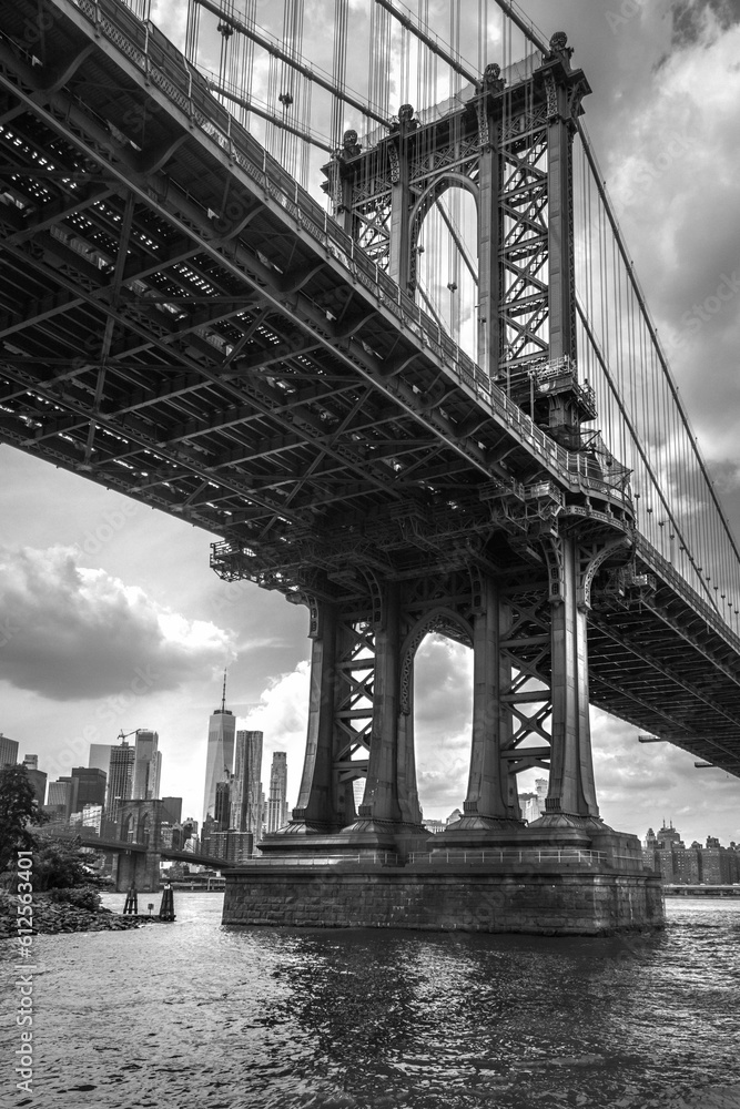 Brooklyn Bridge over The East River in New York, with a cityscape in the background, in a grayscale
