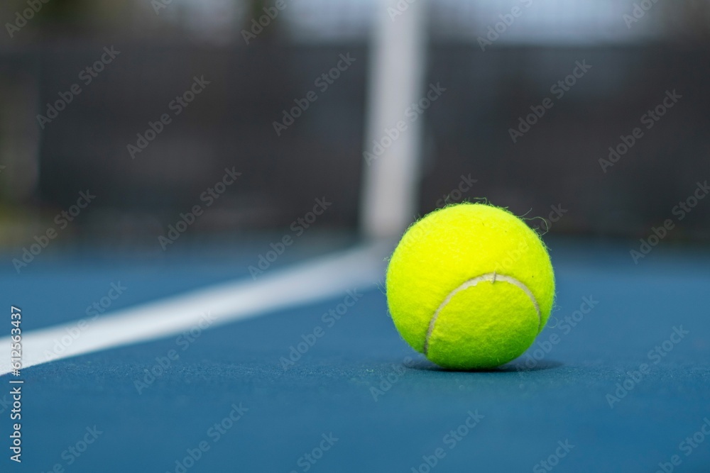 Closeup of a tennis ball on the court on a sunny day with a blurry background