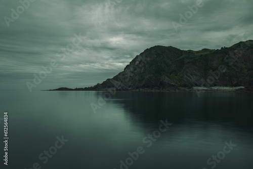 Mysterious gloomy landscape of the sea and rocky mountains in the background on a cloudy day