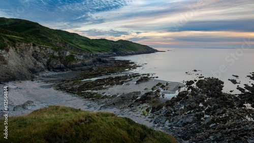 Shore covered with rocky mountains with a sea in the background during sunset