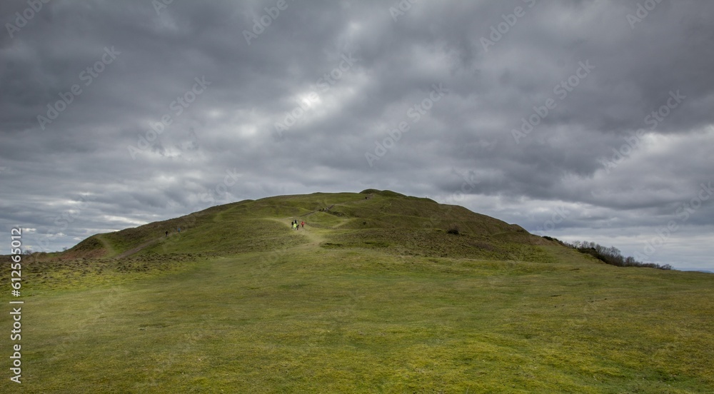 Person coming down the hill with a cloudy sky on the horizon