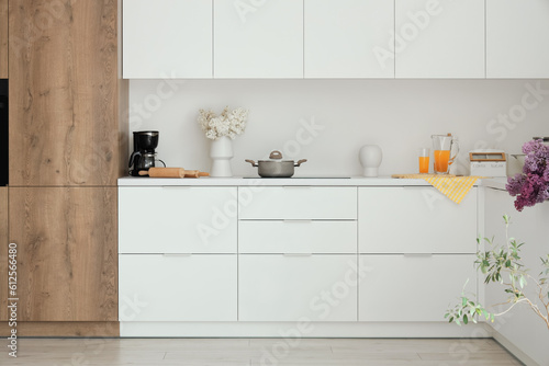 Interior of light kitchen with white counters and flowers