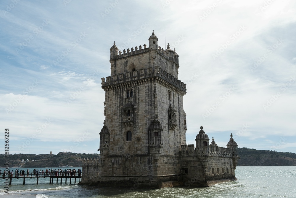 Low-angle of Belem tower with a seascape view with a cloudy, sunlit sky in the background