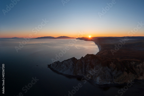Beautiful sunset seascape. Aerial view of rocky cape and sea bay. Evening sun over the coast. Popular natural tourist attraction. Cape Nyuklya, Sea of Okhotsk, Magadan region, Far East of Russia.